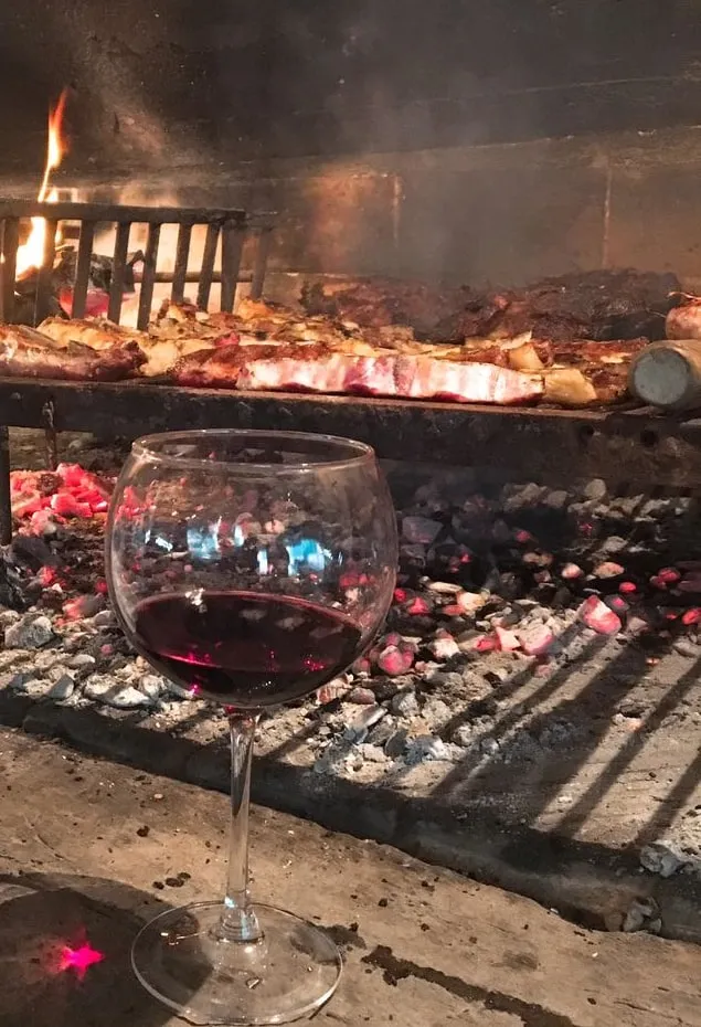 Parrilla encendida con carne asándose en el quincho de Argenplugs